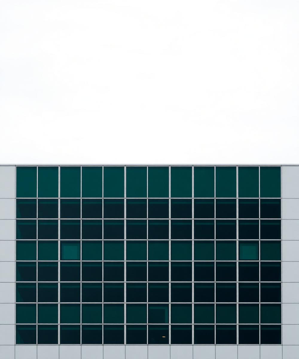 Rasterfassade eines modernen Gebäudes mit dunkelgrün getönten Glasflächen